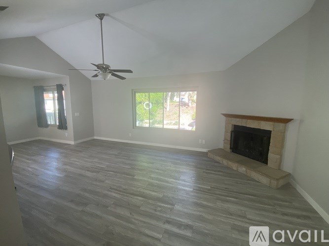 A spacious living room with a fireplace and a ceiling fan.