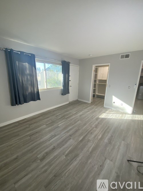 A room with wooden flooring and a window with blue curtains.