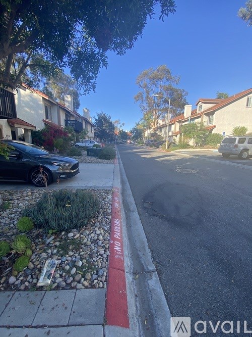 A street with a red curb and a car parked on the side.