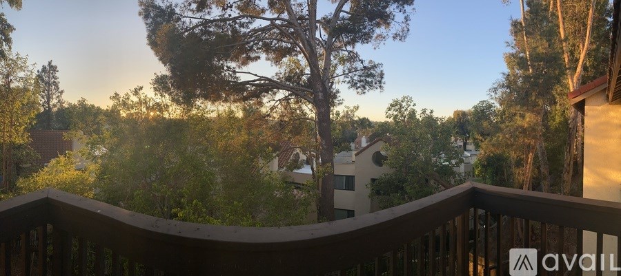 A balcony overlooks a residential area with houses and trees.