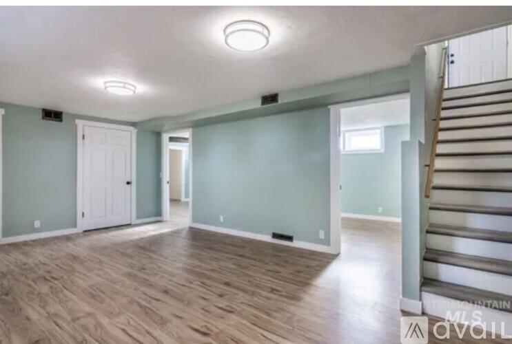 A room with wooden floors and a staircase on the right side.