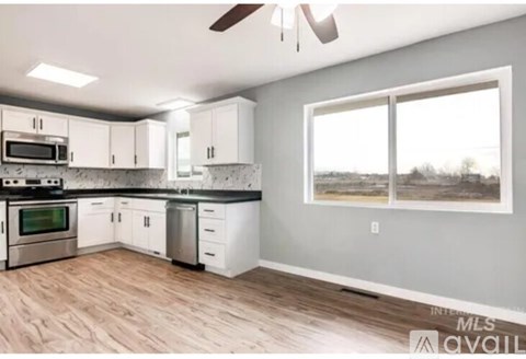 A kitchen with white cabinets and a wood floor.