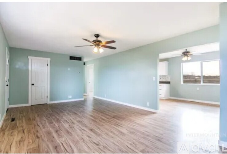 A spacious room with a ceiling fan and lighting fixture.