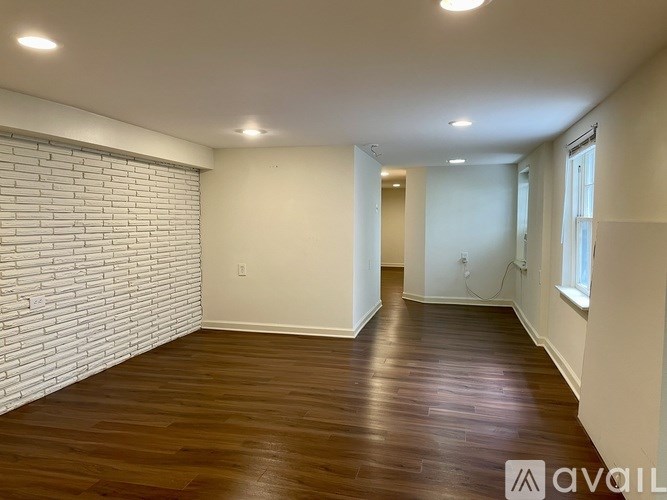 A room with wooden flooring and a white brick wall.