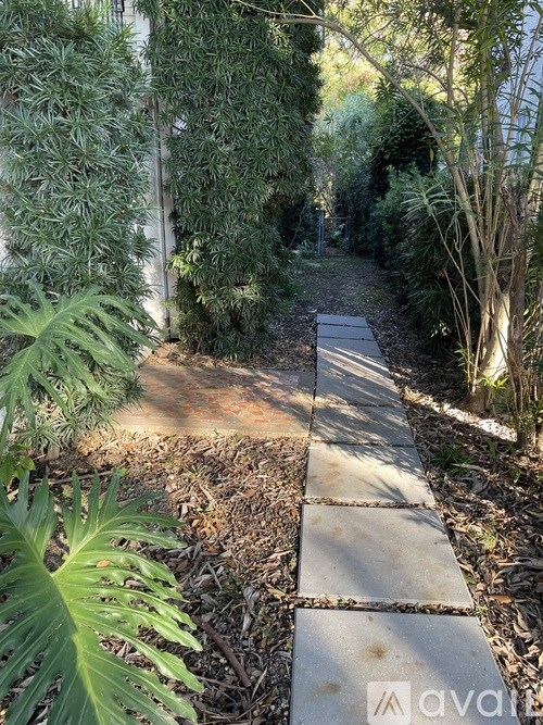 A stone pathway leads through a lush green garden.