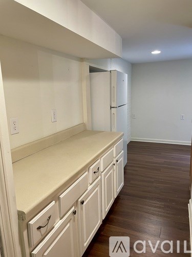 A kitchen with white cabinets and a refrigerator.