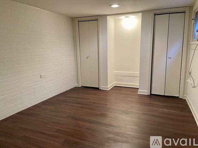 A room with wooden flooring and white walls with two doors.