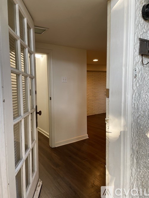 A white door with a black handle is open to a hallway.
