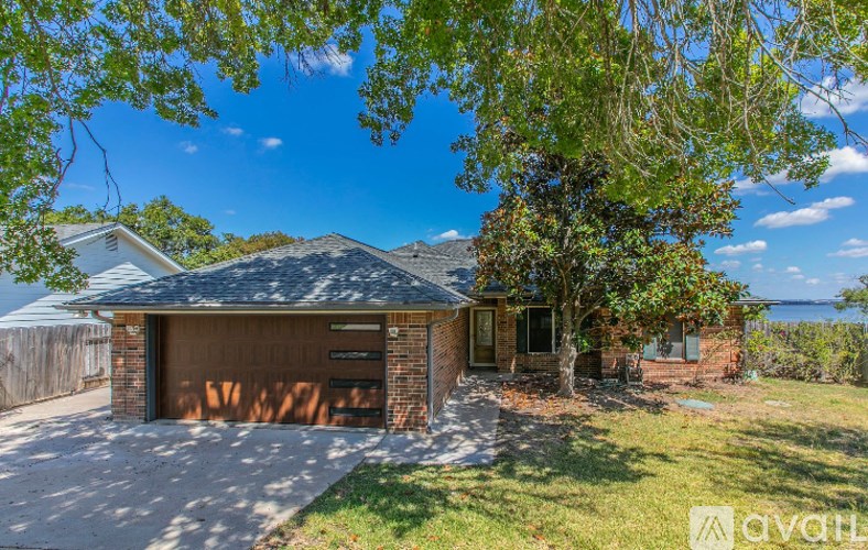 A house with a garage and a tree in front of it.