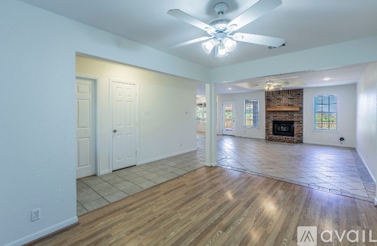 A spacious living room with a fireplace and a ceiling fan.
