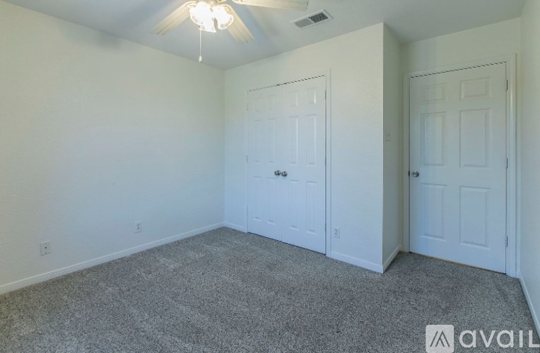 A room with a carpeted floor and two doors.