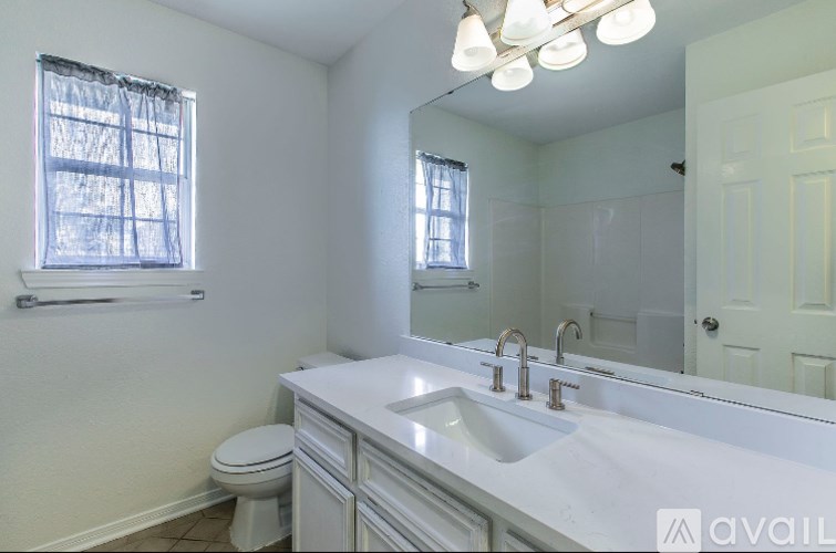 A white bathroom with a toilet, sink, and mirror.