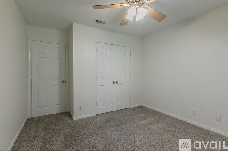 A room with a ceiling fan and two doors.