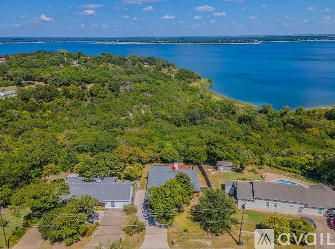 A bird's eye view of a residential area with houses and a large body of water in the distance.