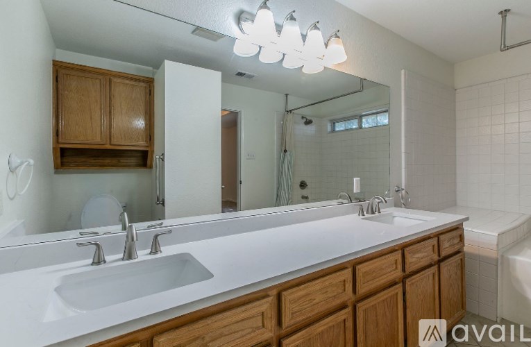 A bathroom with a white sink and wooden cabinets.