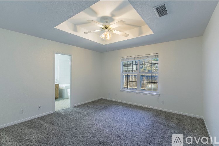 A spacious room with a ceiling fan and a window with blinds.