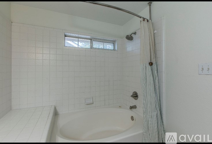A white bathroom with a tub and a window.