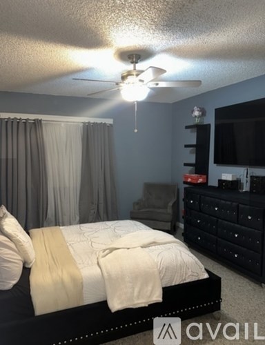 A bedroom with a bed, a chair, and a television.
