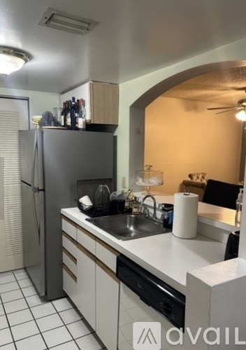A kitchen with a refrigerator, sink, and a counter.