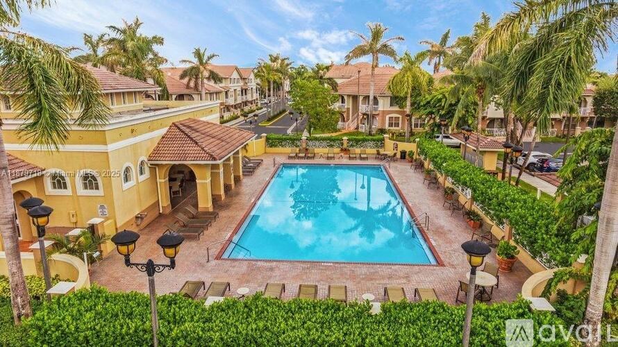 A large swimming pool surrounded by palm trees and a building.