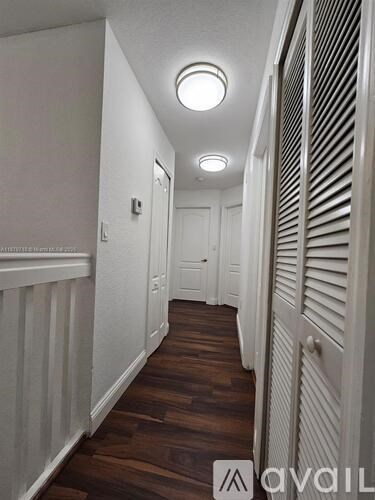 A hallway with wooden floors and white walls.