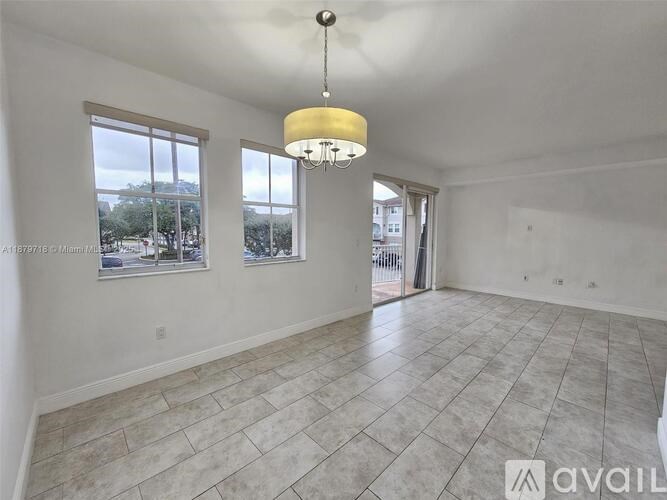 A spacious room with tiled flooring and a chandelier hanging from the ceiling.