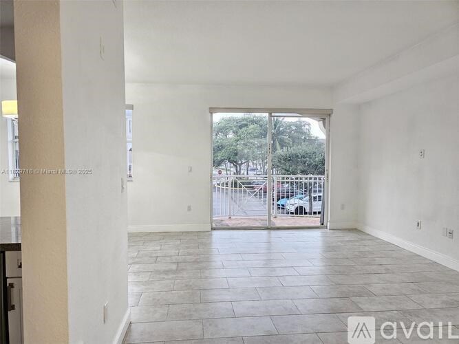 A spacious room with tiled flooring and a view of a parking lot through a glass door.