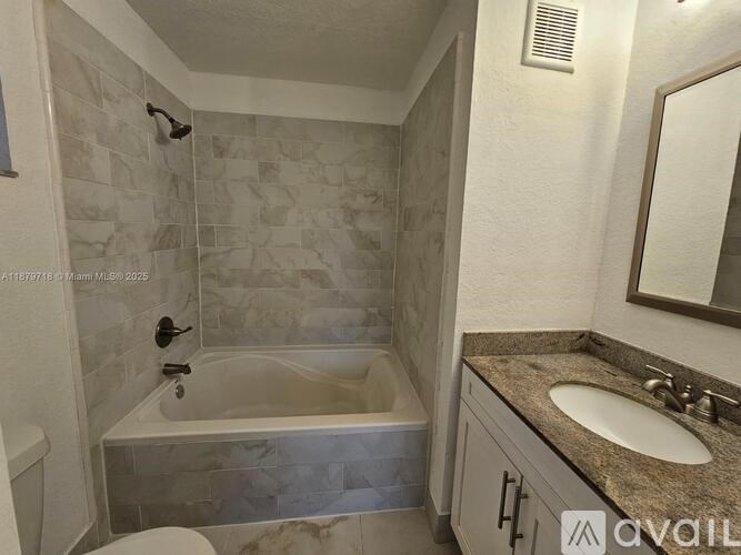 A bathroom with a tub, sink, and mirror.