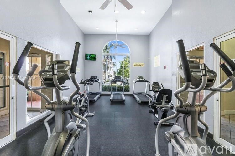 A gym with a row of treadmills and exercise bikes.