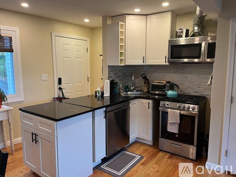 A kitchen with white cabinets and black countertops.