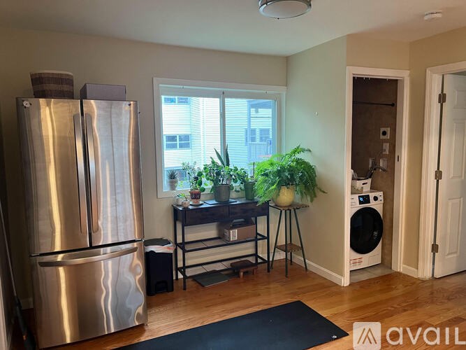 A kitchen with a stainless steel refrigerator and a black mat on the floor.