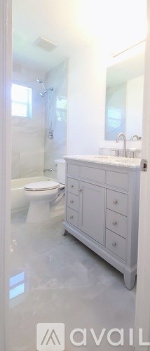 A white bathroom with a toilet, sink, and mirror.