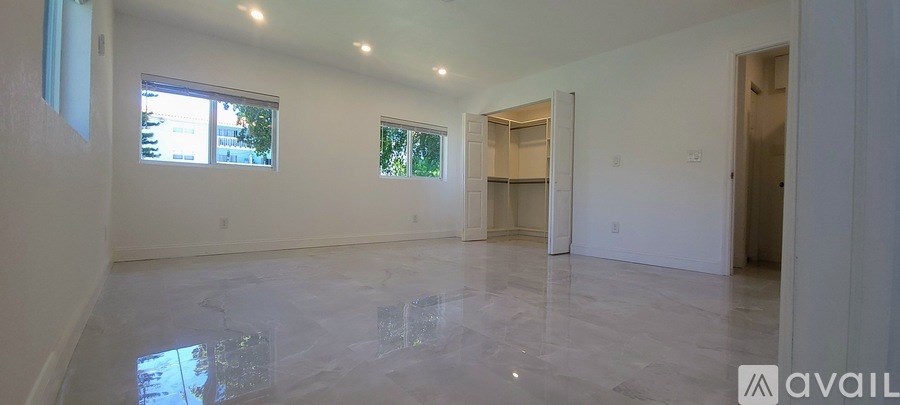 A large, empty room with a tiled floor and a window on the left wall.