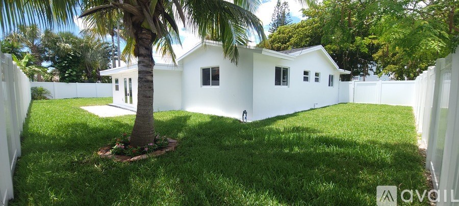 A white house with a palm tree in front.