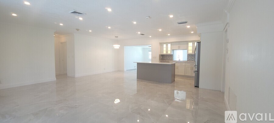 A spacious, empty room with a kitchen area in the background.