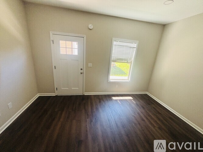 A room with a wooden floor and a window with blinds.