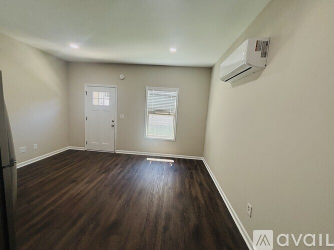 A room with a wooden floor and an air conditioner on the wall.