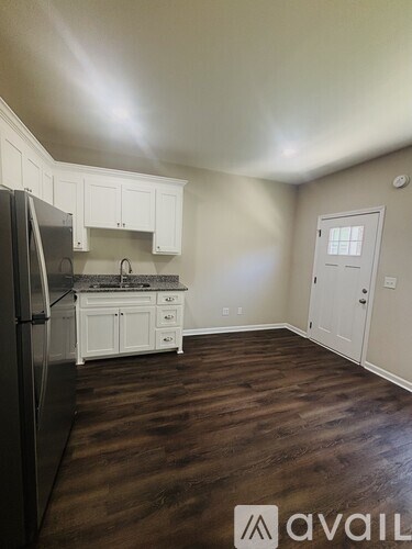 A kitchen with white cabinets and a black fridge.