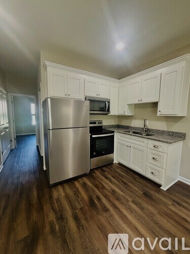 A kitchen with white cabinets and a wooden floor.