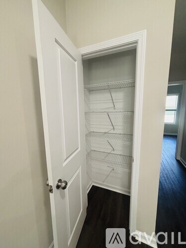 A white door is open to a room with a white shelving unit.
