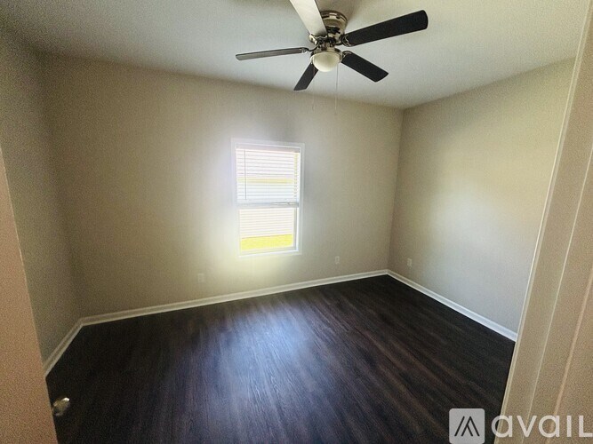 A room with a ceiling fan and a window letting in light.