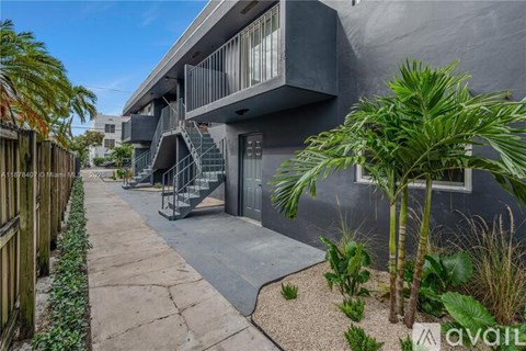 A modern building with a concrete staircase and a small garden in front.