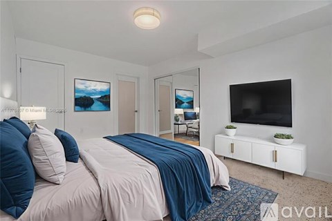 A bedroom with a bed, a chair, and a television.