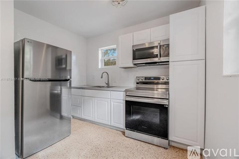 A kitchen with a stainless steel refrigerator, microwave, and oven.