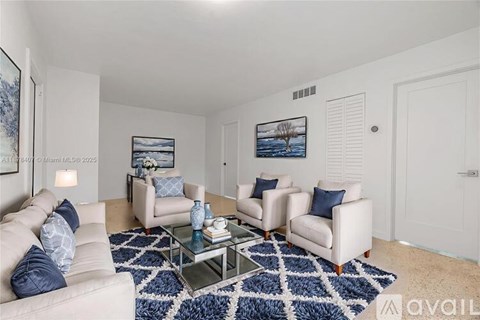A living room with a white couch, two chairs, and a coffee table.