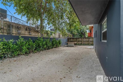A backyard with a gravel ground and a fence.
