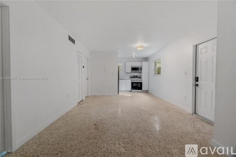 A spacious living room with a kitchen in the background.