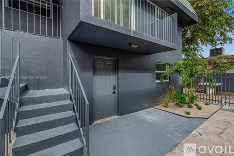 A modern house with a grey exterior and a black door.