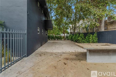 A black building with a gate and a bench in front.