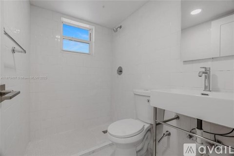 A white bathroom with a toilet, sink, and shower.